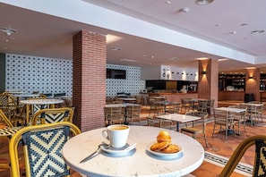 A spacious indoor cafe with round tables and wicker chairs, featuring a modern design with brick accents and patterned walls. - Estival Park Marena (Vila-Seca)