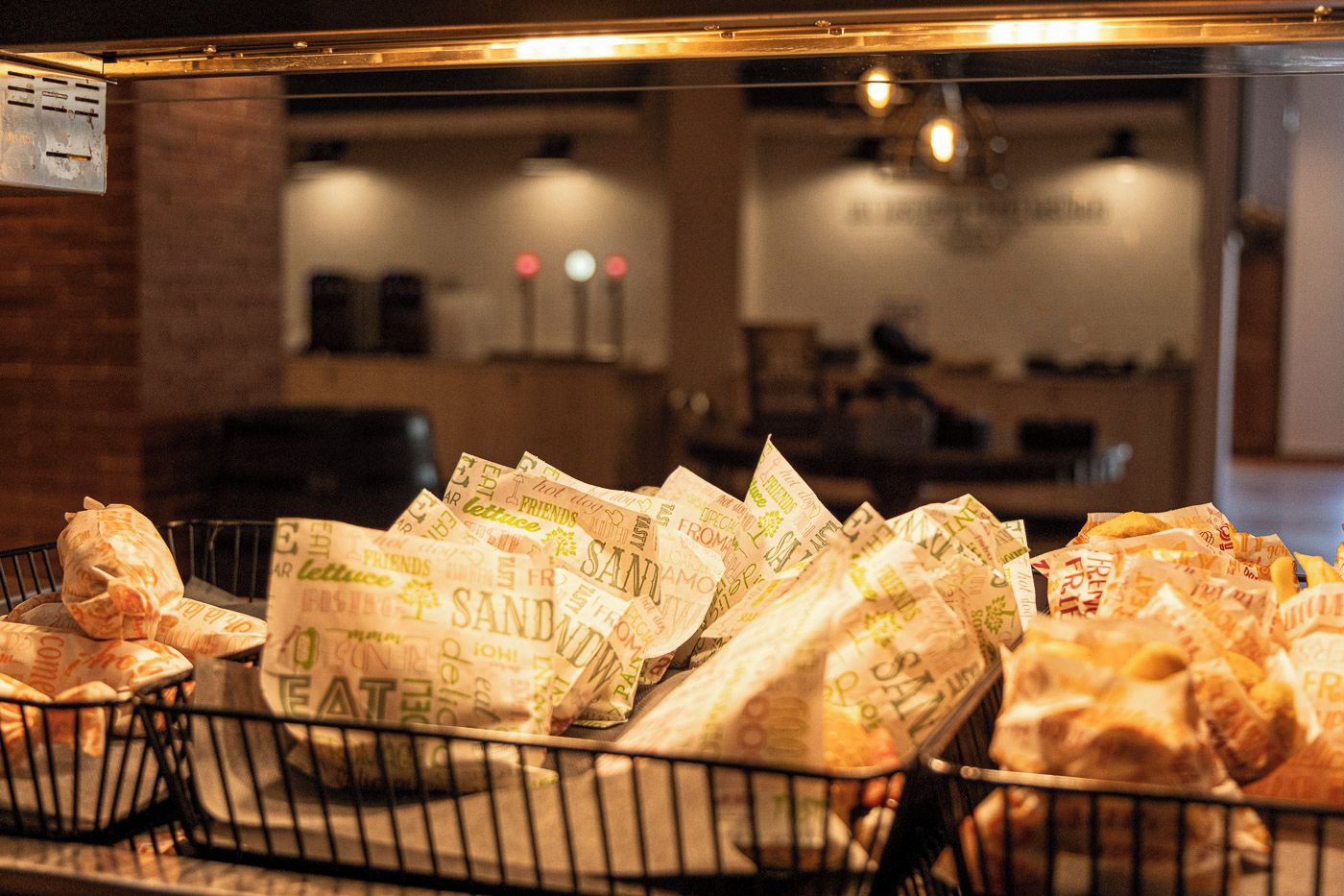 Un expositor con diversos alimentos, incluyendo sándwiches y otros productos envasados, en un restaurante.
