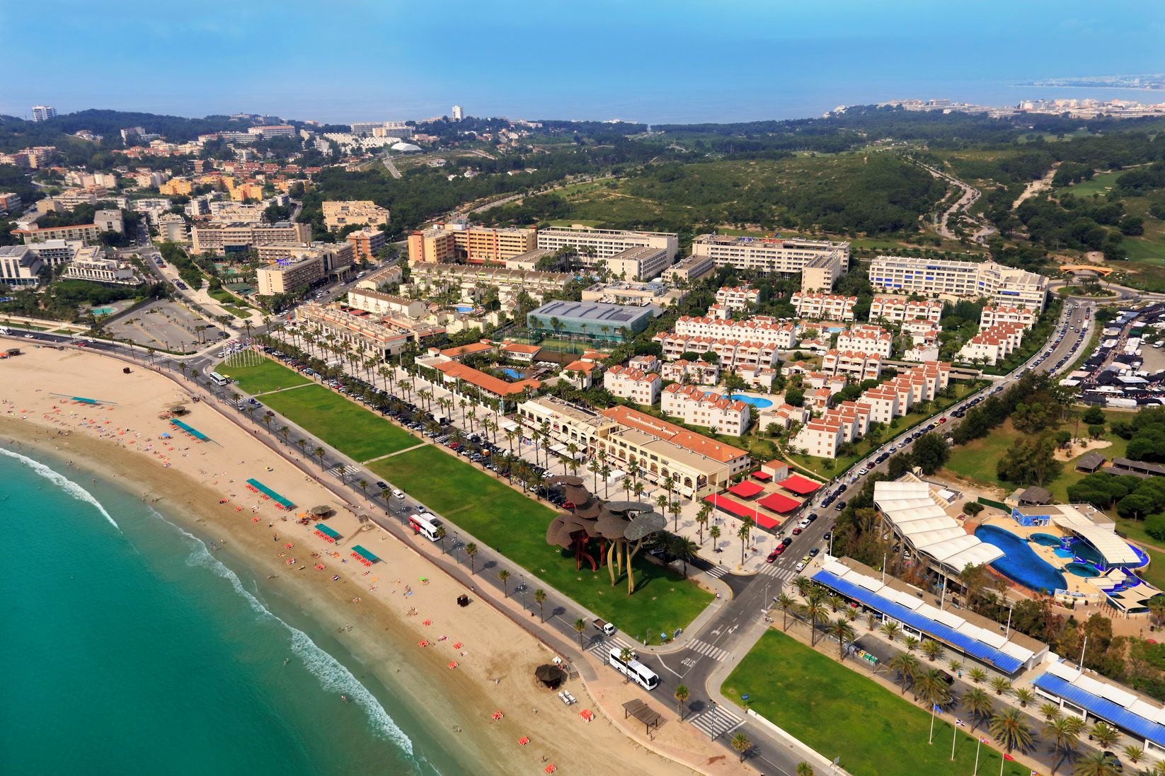 Vue aérienne d’une station balnéaire avec une plage, des bâtiments d’hôtel et une piscine.