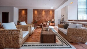 Un espace de détente moderne avec des meubles en osier, une table basse centrale et un sol à motifs.