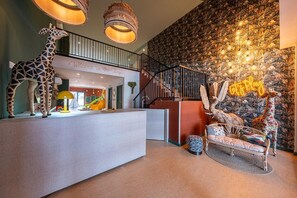 A reception area with a giraffe sculpture, a staircase, and a wall with a jungle-themed mural. - Estival Park Marena (Vila-Seca)