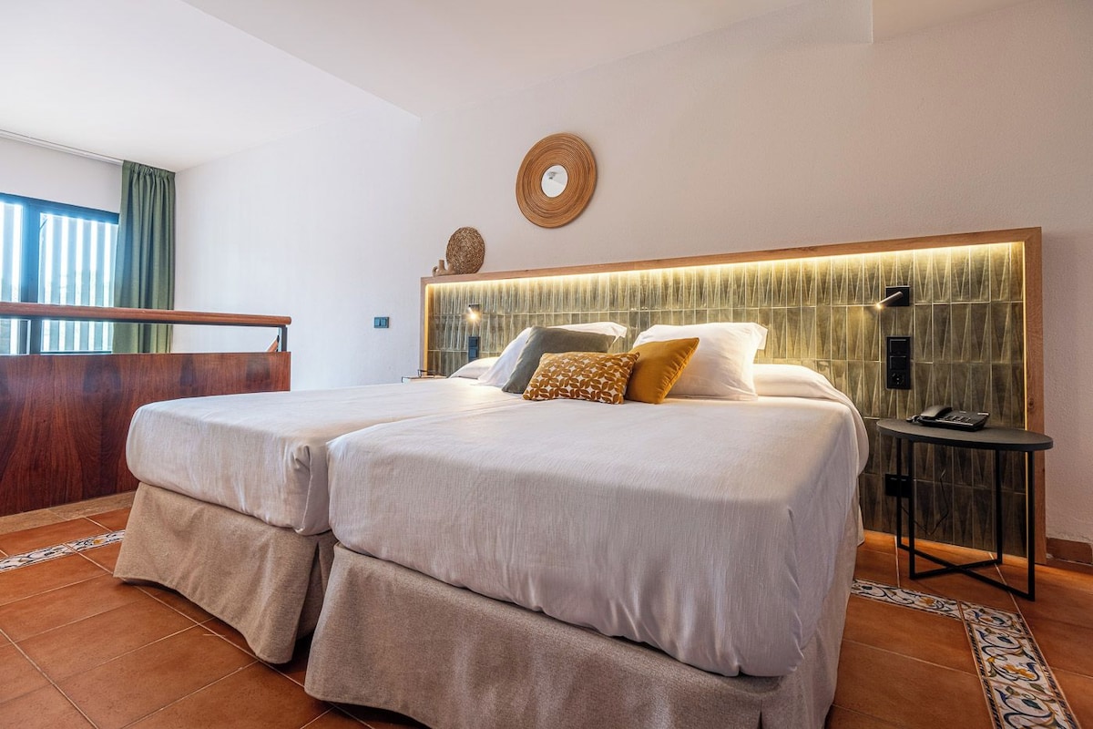 A hotel room with a large bed, a desk, and a view of the outdoors.