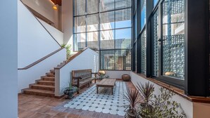 Un espace intérieur spacieux avec un escalier, un banc en bois et des plantes en pot.