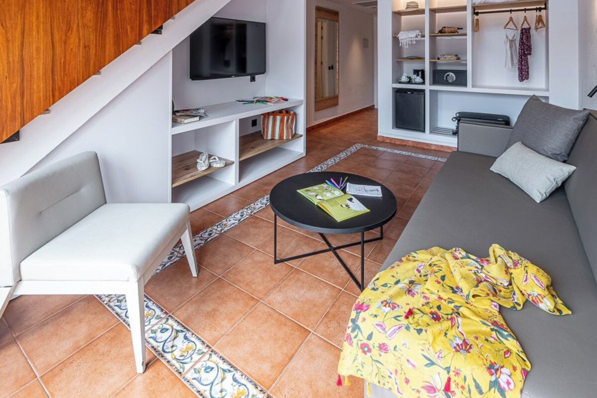 A modern living room with a staircase, a sofa, a coffee table, and a TV.