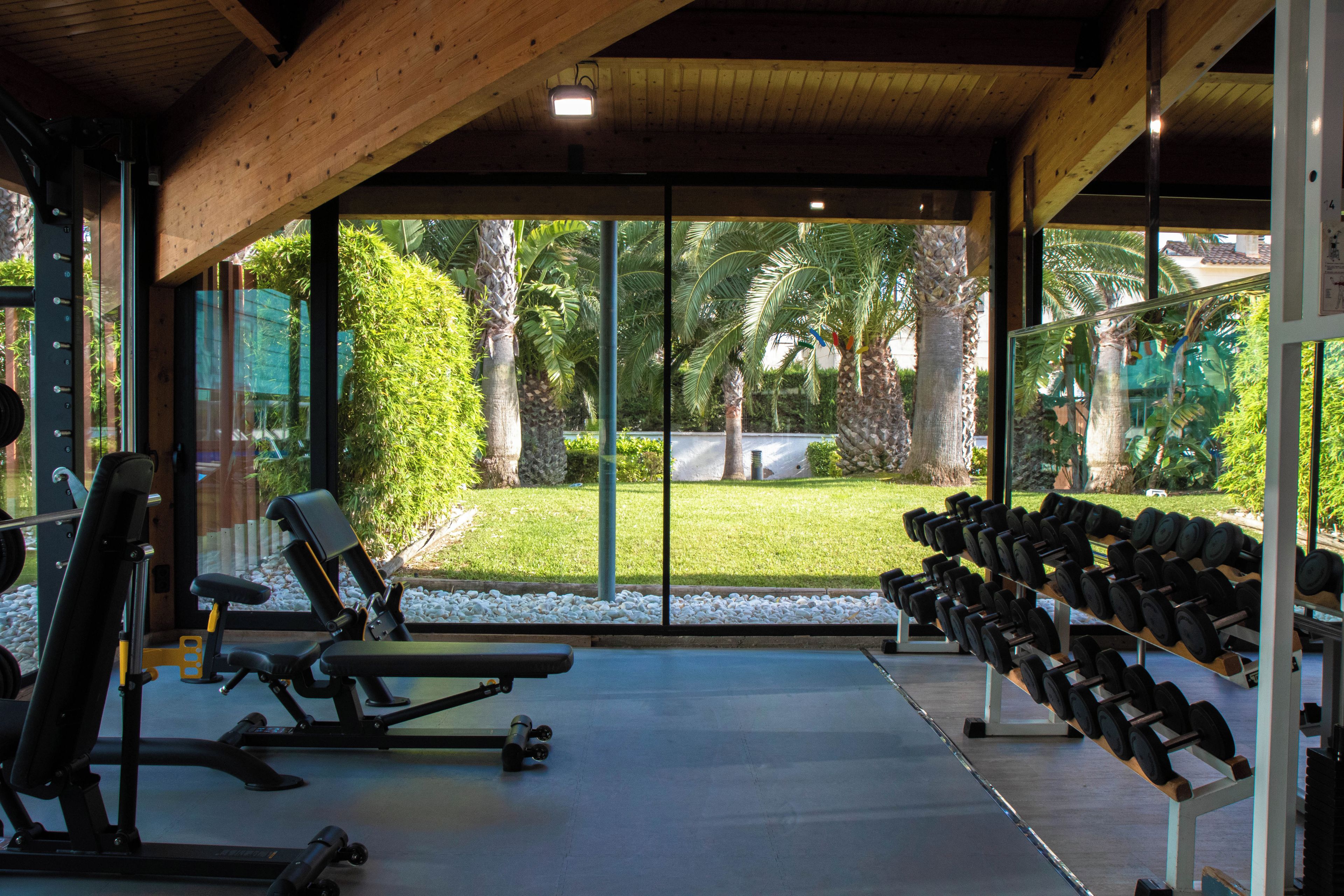 Un gimnasio con equipo de ejercicio y vistas a un jardín.