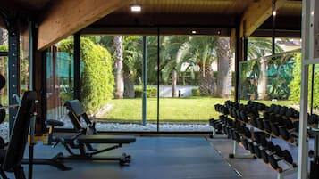 Un gimnasio con equipo de ejercicio y vistas a un jardín.