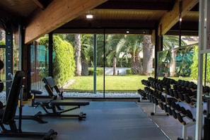 A gym with exercise equipment and a view of a garden. - Estival Park Marena (Vila-Seca)