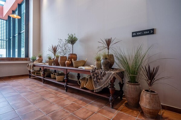 A hallway with a wooden bench displaying various potted plants and baskets. A sign indicates room numbers 3047 and 3064. - Estival Park Marena (Vila-Seca)