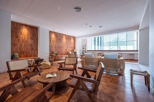 Amplia sala de estar con piso de madera, mobiliario de mimbre y grandes ventanales que dejan entrar luz natural.
