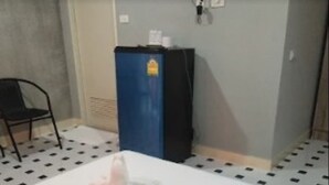 Um quarto com uma mesa branca, um armário azul e uma cadeira preta.