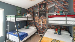 Ein Schlafsaalzimmer mit Etagenbetten, einer Ziegelwand und Harry-Potter-Dekorationen.