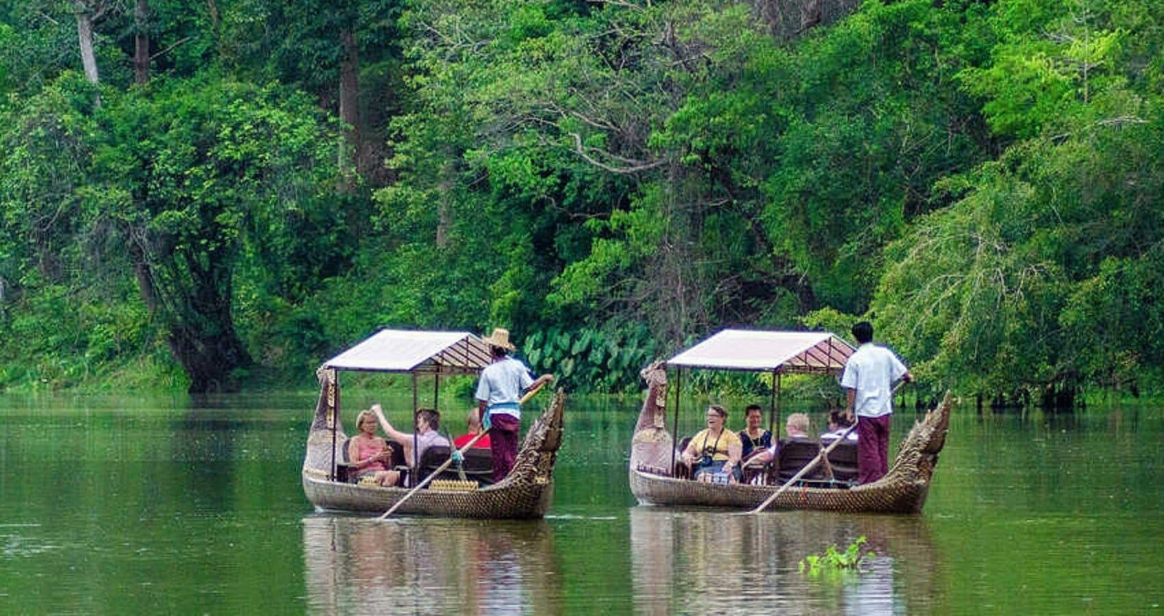 Two traditional boats with passengers, surrounded by dense greenery.