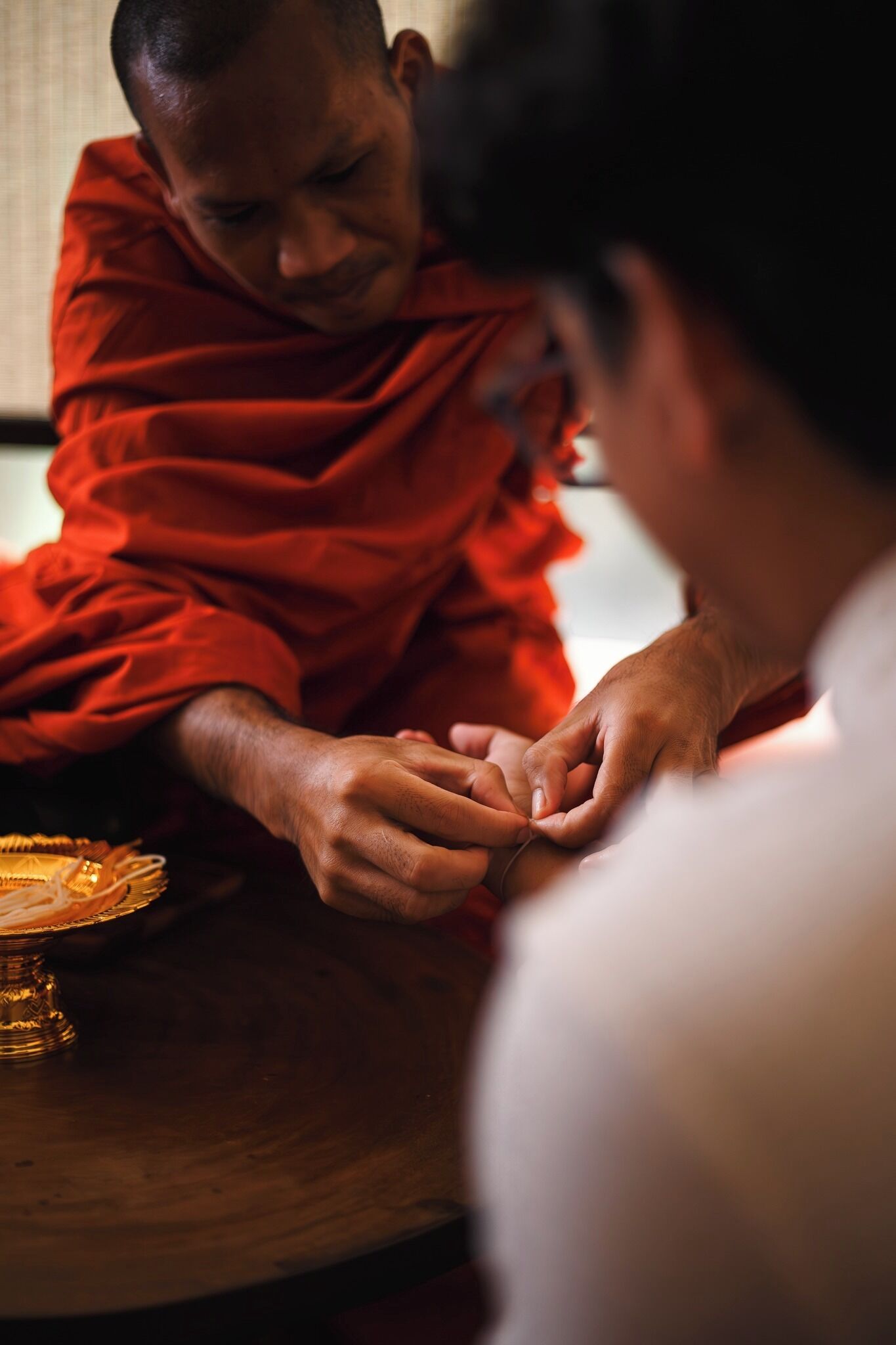 Un moine vêtu d’une robe rouge effectue un rituel en compagnie d’une personne.