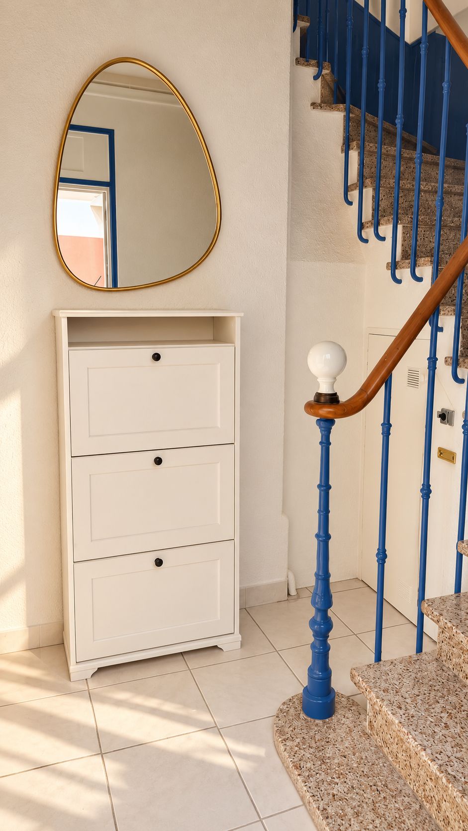 A staircase with blue balusters and a white wall-mounted mirror.