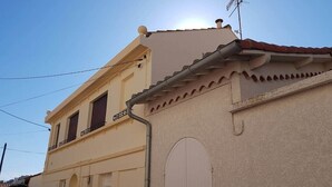 Un bâtiment à deux étages, doté d’un toit plat, d’un balcon et d’une grande porte en arc de cercle.