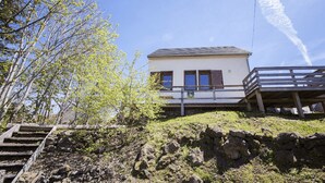 A two-story building with a balcony, situated on a rocky hillside with sparse vegetation.