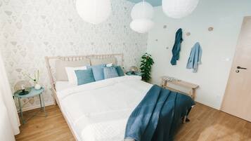 A bedroom with a bed, bedside table, hanging lights, and a wall with a pattern.