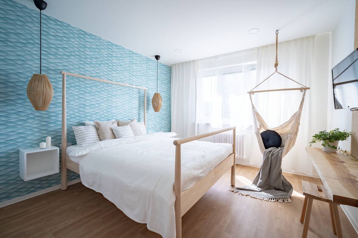 Ein Schlafzimmer mit einem Bett, Nachttischen, einem Hängesessel und einem Fernseher.
