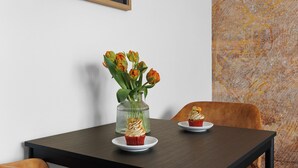 Une table à manger ornée d’un vase de tulipes et de deux petits gâteaux sur des assiettes blanches.