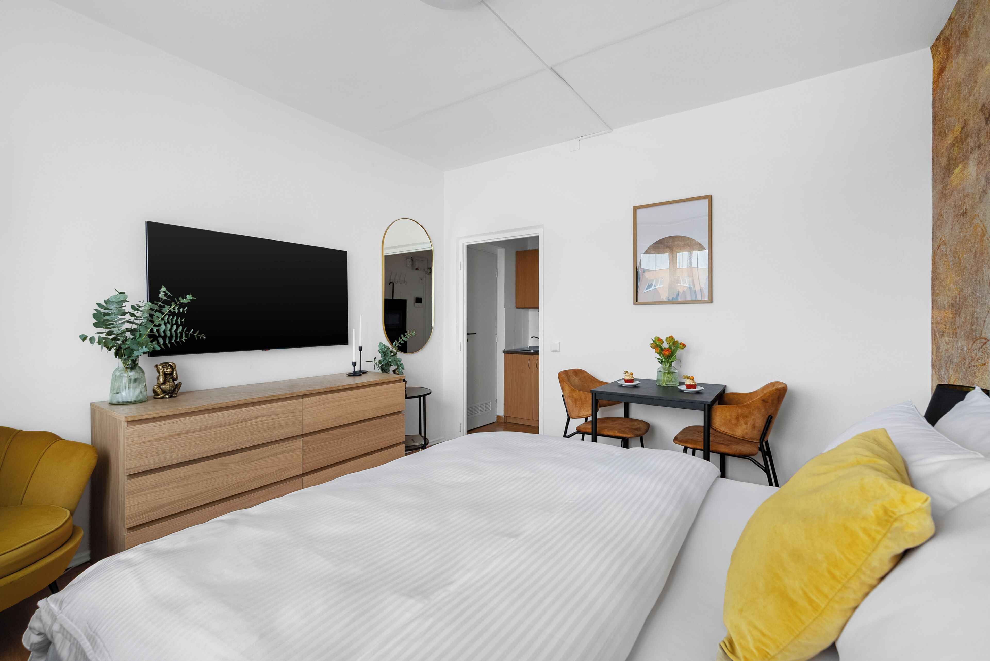 Une chambre d’hôtel moderne dotée d’un grand lit, d’un bureau avec deux chaises, d’une télévision à écran plat et d’un petit coin repas.