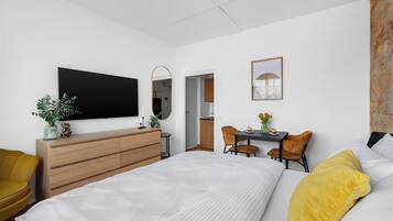Une chambre d’hôtel moderne dotée d’un grand lit, d’un bureau avec deux chaises, d’une télévision à écran plat et d’un petit coin repas.