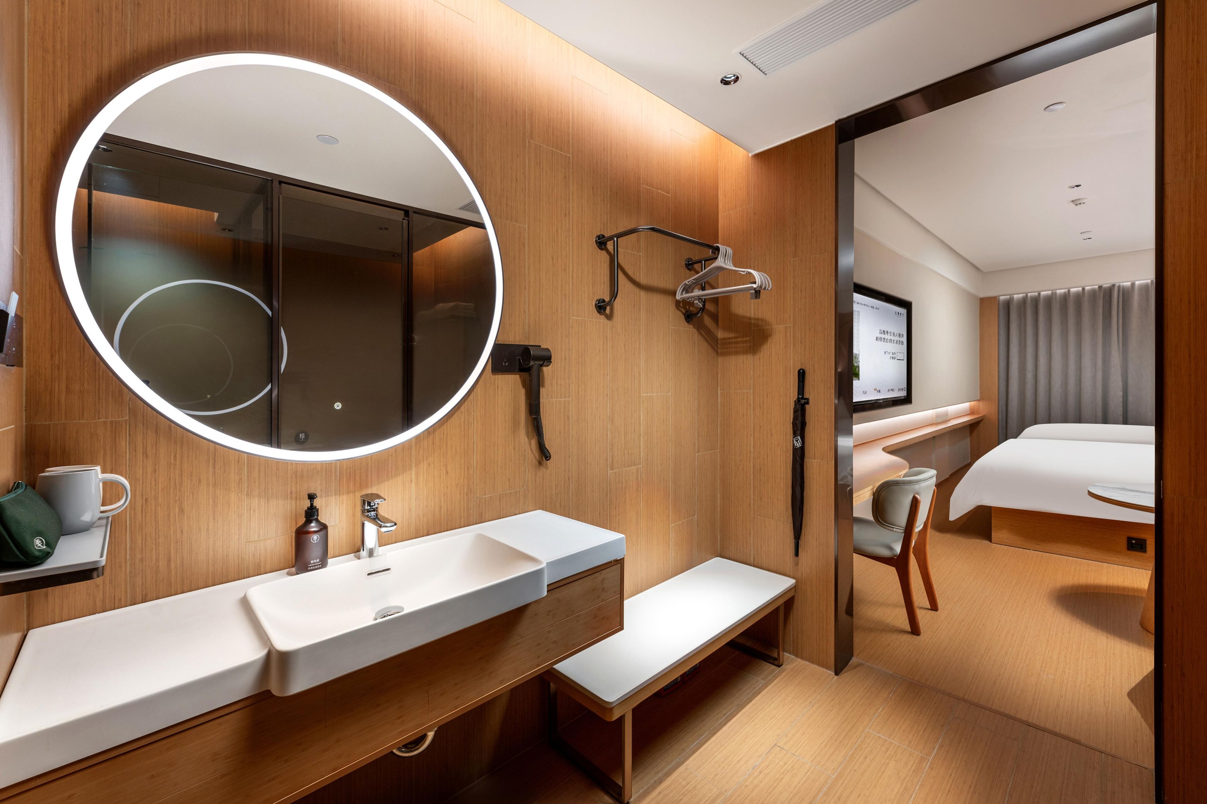 A modern bathroom with a large mirror, a sink, and a bench.