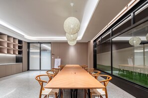 A conference room with a long wooden table, wicker chairs, and a modern chandelier. - Ji Hotel (Guangzhou)