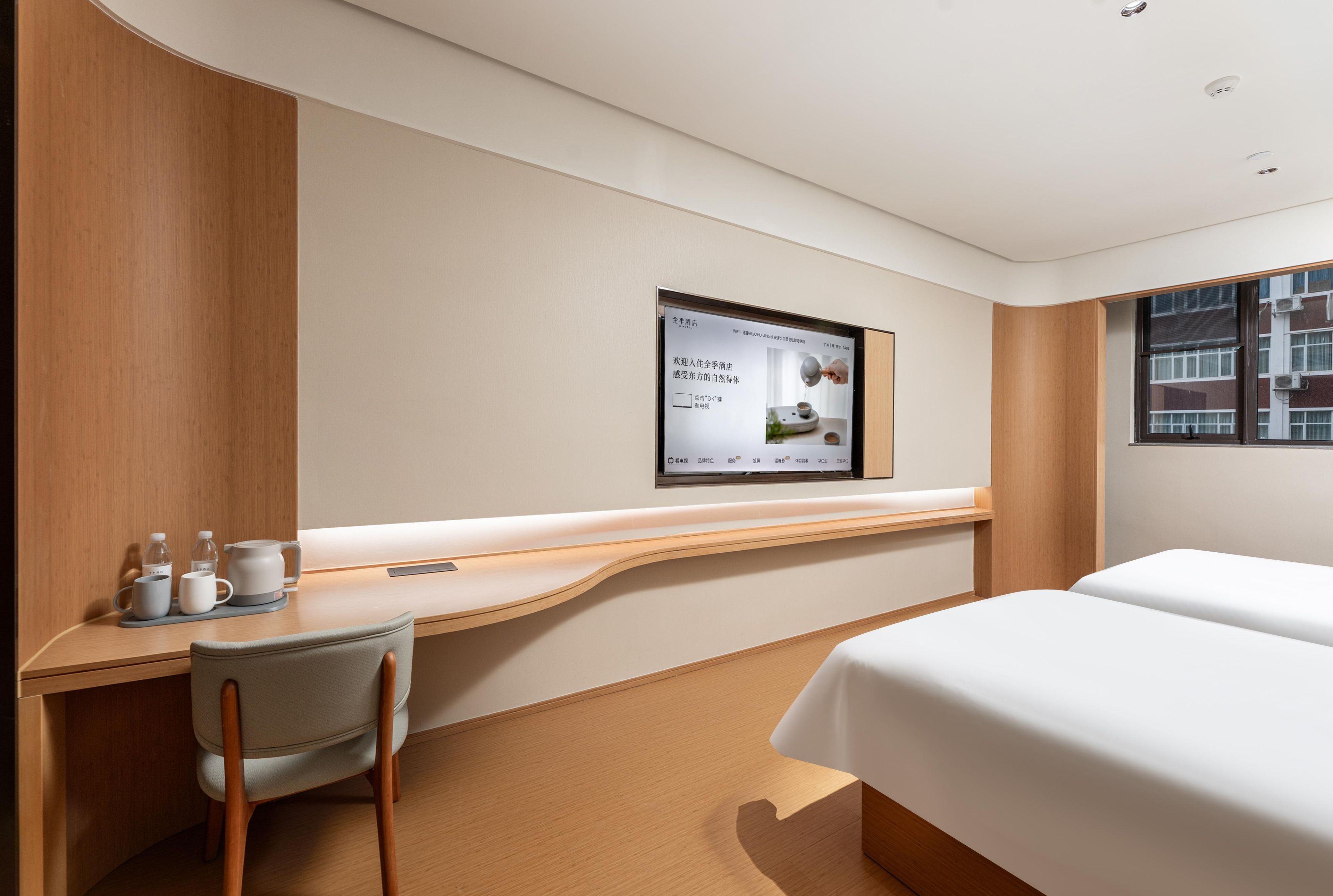 Une chambre d’hôtel avec un bureau en bois, une chaise, un lit et une fenêtre.