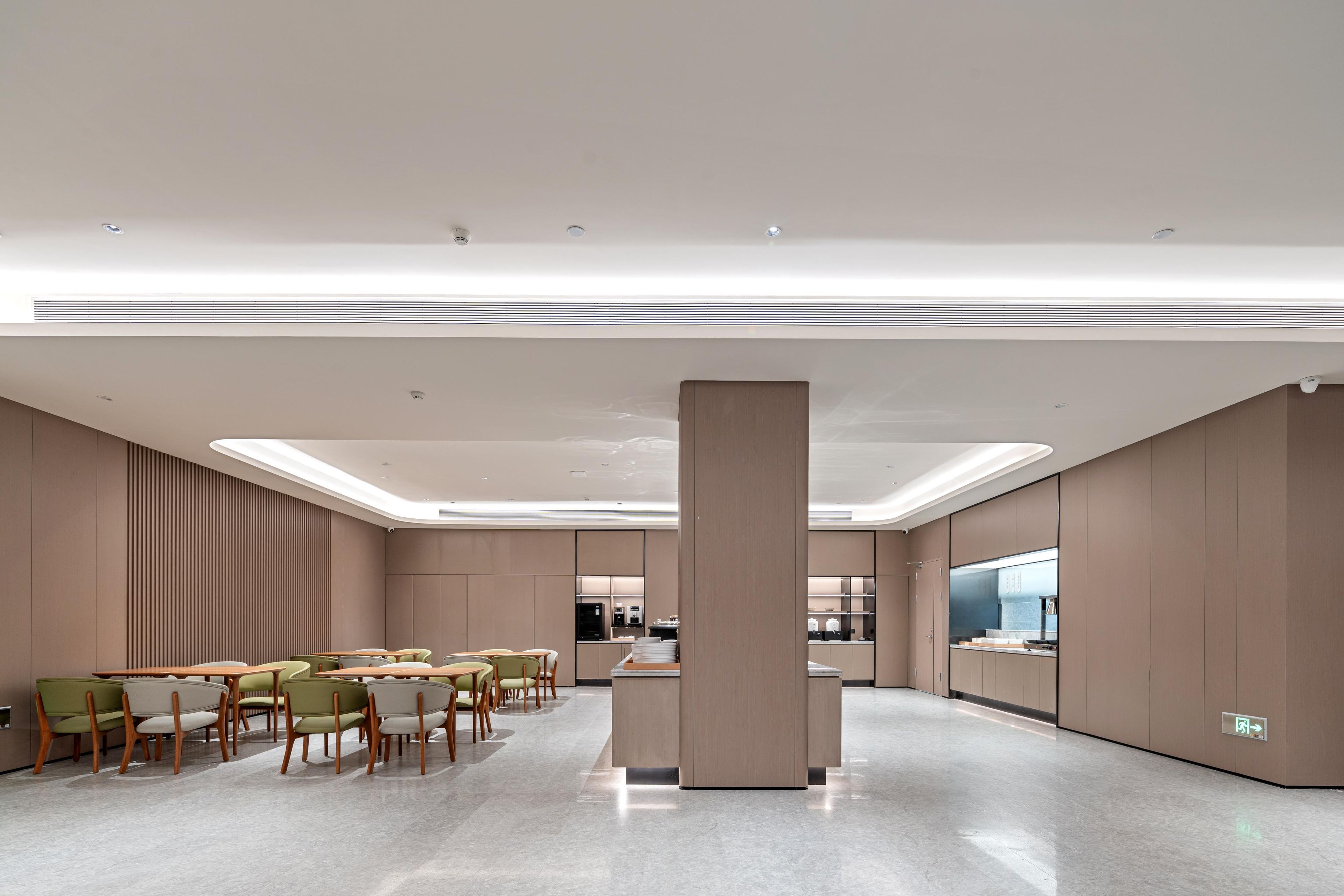 A modern hotel lobby with a central seating area, a kitchenette, and a large pillar.