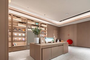 A modern interior with a reception desk, shelves with products, and a potted plant. - Ji Hotel (Guangzhou)