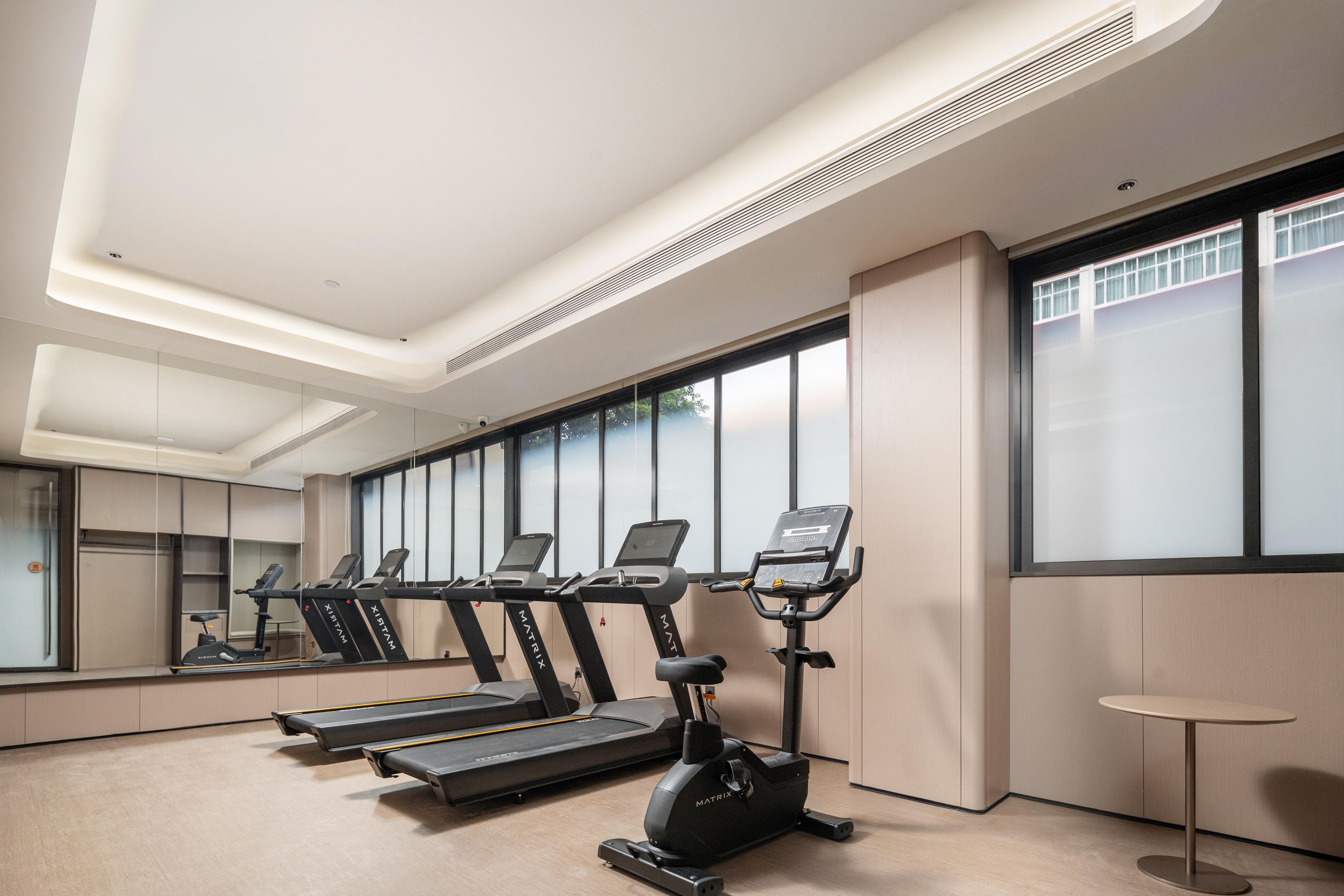 A modern fitness room with treadmills, an elliptical, and a small table.