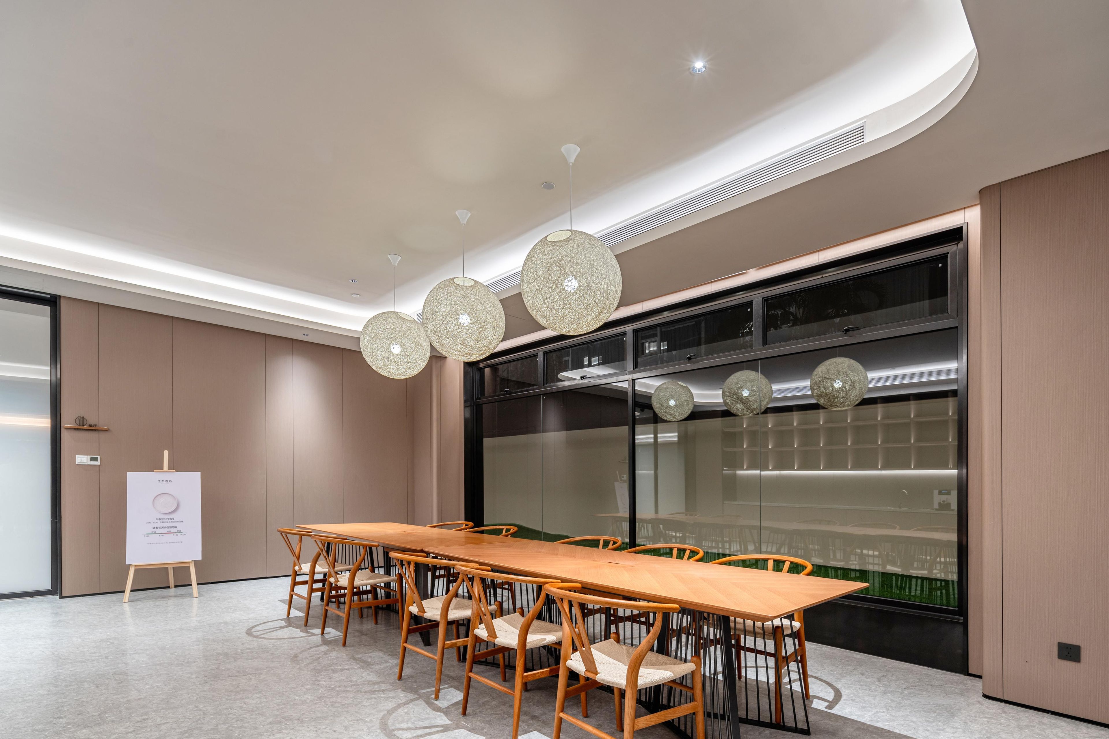 A modern conference room with a long wooden table, four chairs, and three spherical pendant lights.