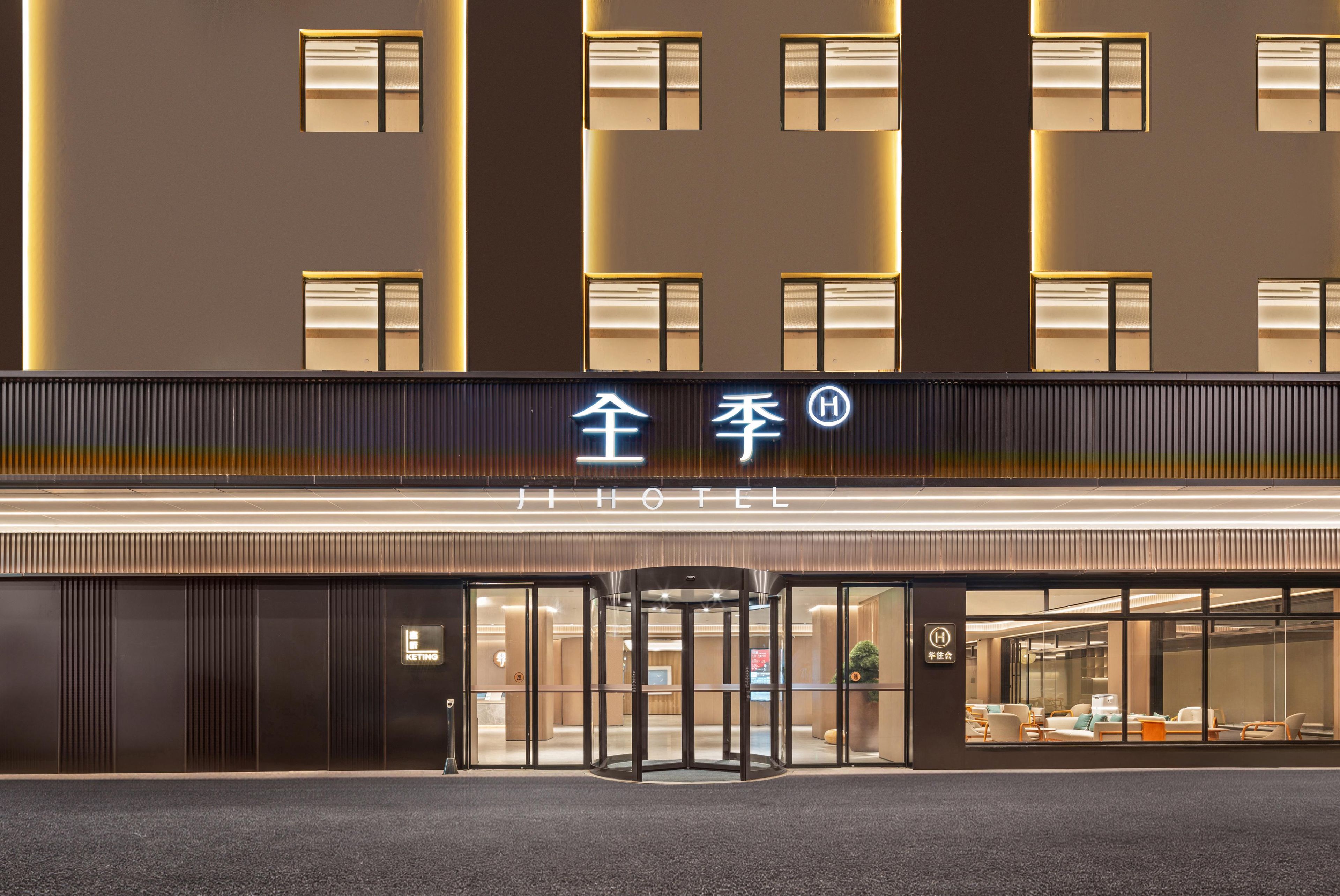 L’entrée d’un hôtel, avec une porte tournante, une enseigne avec des caractères chinois et un design moderne.