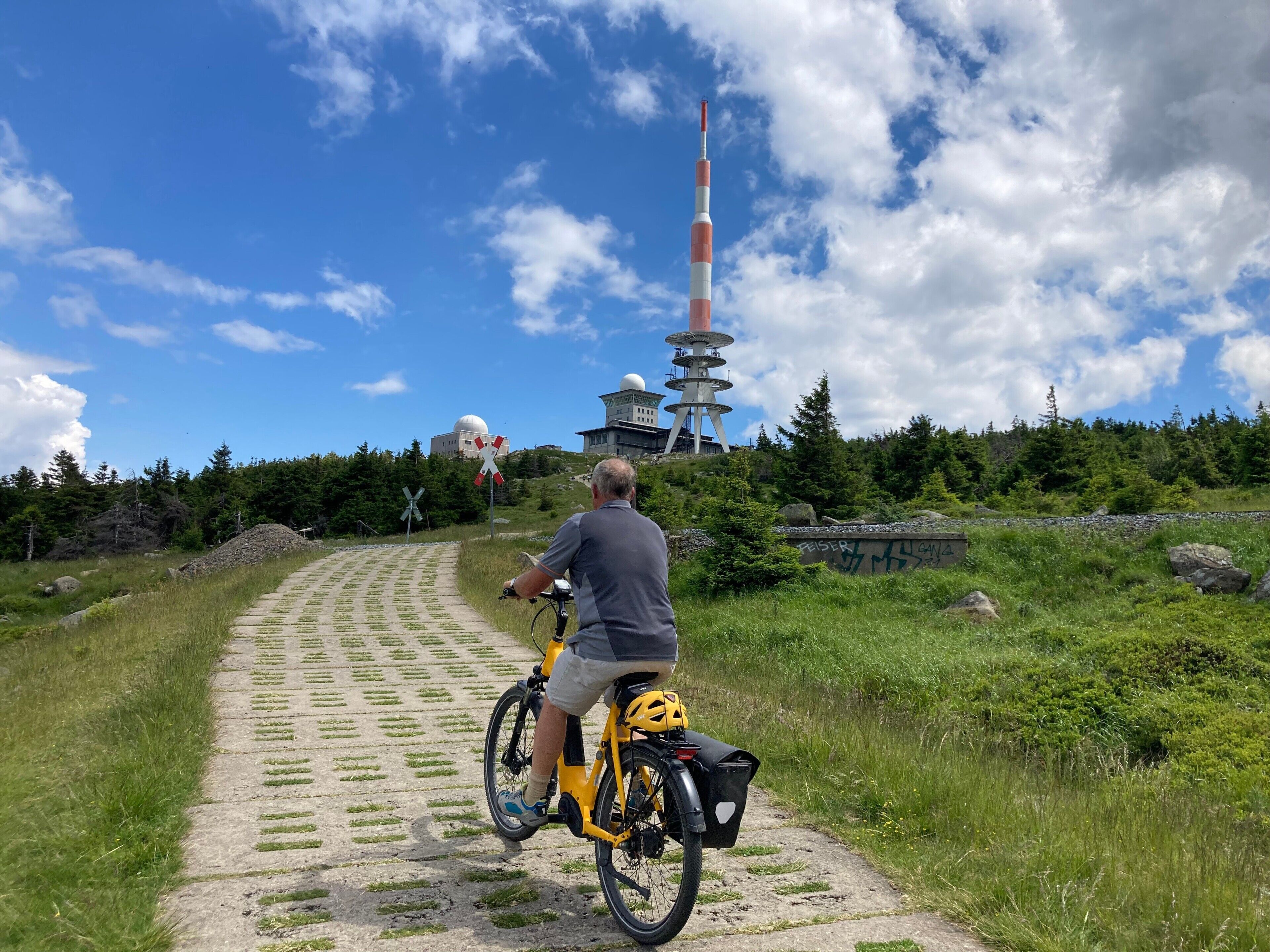 En man cyklar på en asfalterad stig med ett torn i bakgrunden.