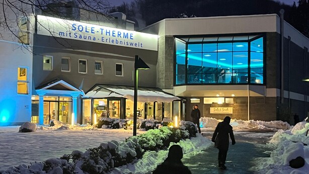 Ein Gebäude mit einem Schild, auf dem 'SOLE-THERME mit Sauna-Erlebniswelt' steht, und einer Glasfassade.
