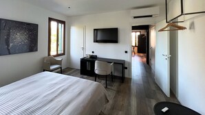Ett modernt hotellrum med en säng, ett skrivbord och en TV.