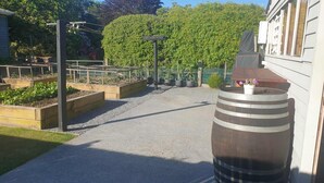 A garden pathway leading to a building with a large barrel and raised garden beds.
