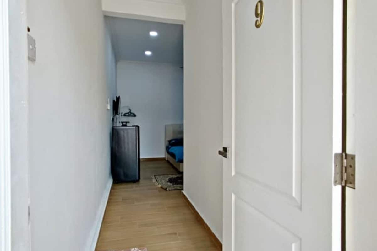 A narrow hallway with a wooden floor, a patterned rug, and a door with the number 9.