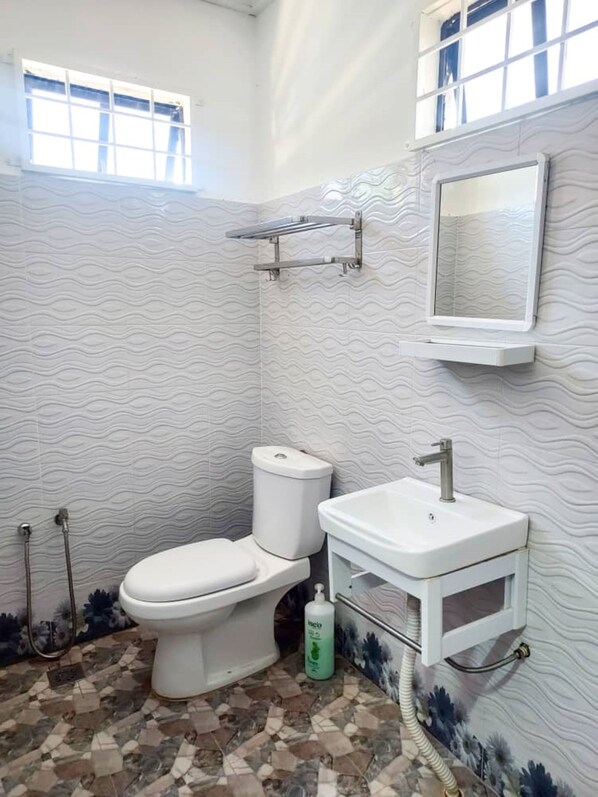Een badkamer met toilet, wastafel en douche.