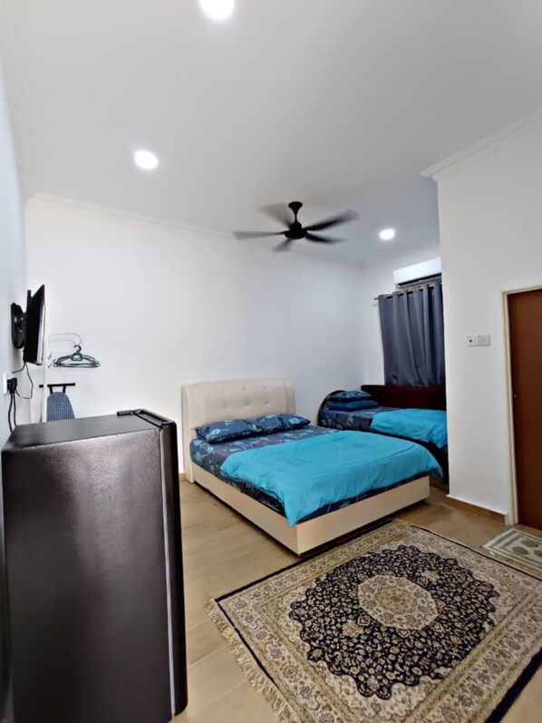 A bedroom with a bed, a ceiling fan, a rug, and a TV stand. - Homestay Bonda (Kuala Terengganu)