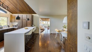 A modern kitchen with a central island, wooden flooring, and pendant lighting. - 10-Acre Wellness Retreat, Pool, Sauna, Ceremony Tent | Fable Sonoma by AvantStay (Santa Rosa)