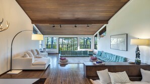 A spacious living area with a wooden ceiling, large windows, and a mix of seating arrangements including sofas and a sectional. - 10-Acre Wellness Retreat, Pool, Sauna, Ceremony Tent | Fable Sonoma by AvantStay (Santa Rosa)