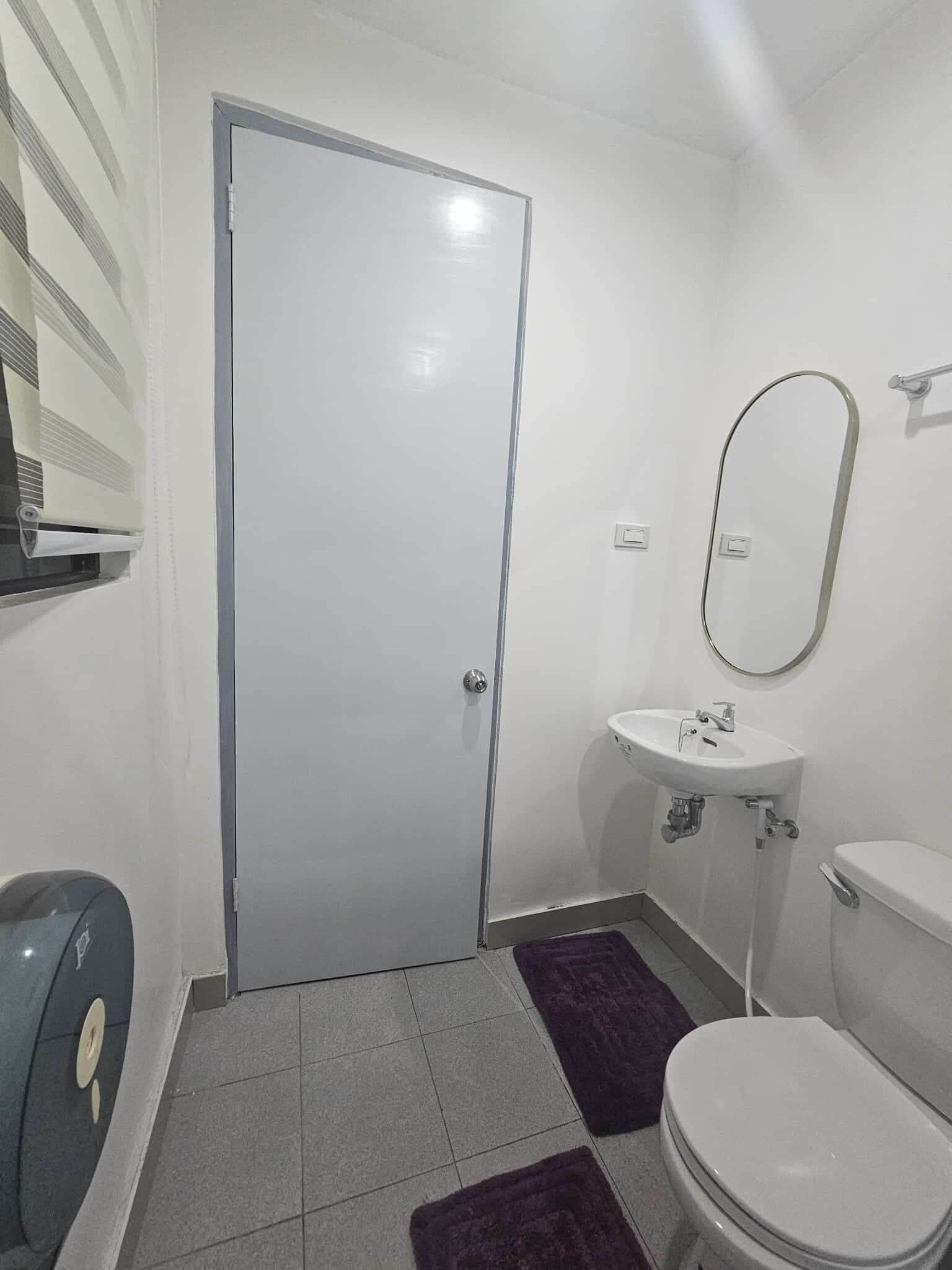 Une petite salle de bain propre, équipée de toilettes, d’un lavabo et d’un miroir.
