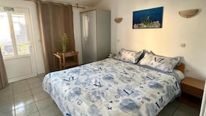 Ett sovrum med en säng, ett skrivbord, en stol, en garderob och en tavla på väggen.