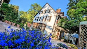 A two-story house with a balcony, surrounded by greenery and potted plants. - Waldhotel Silbermühle (Horn-Bad Meinberg)