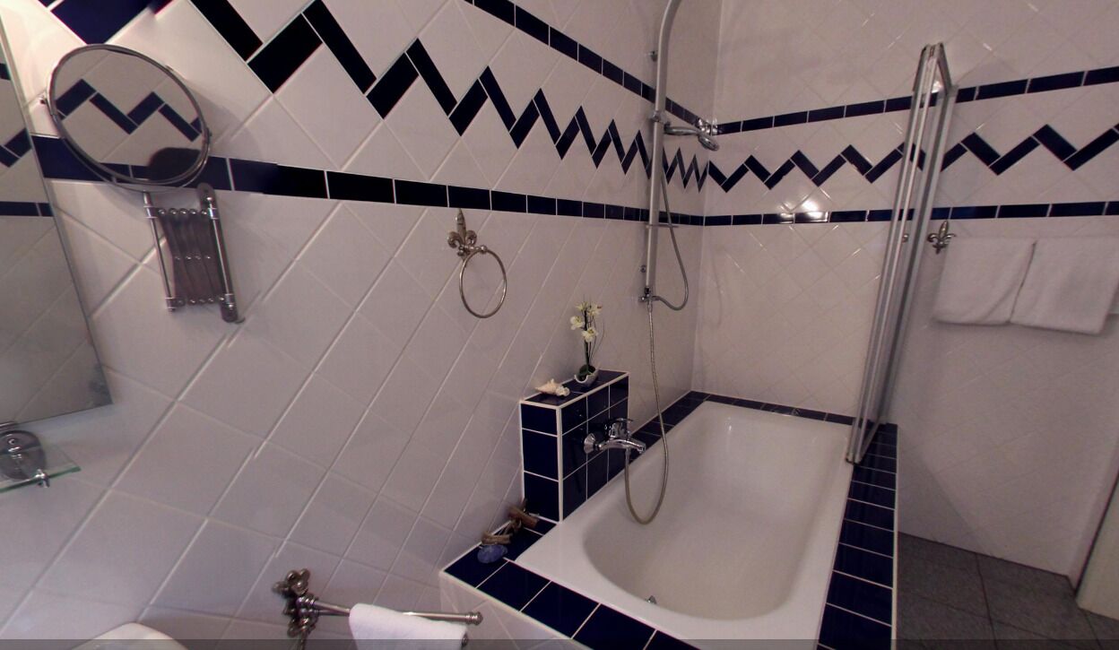 Un baño con bañera, ducha, espejo y toallero.