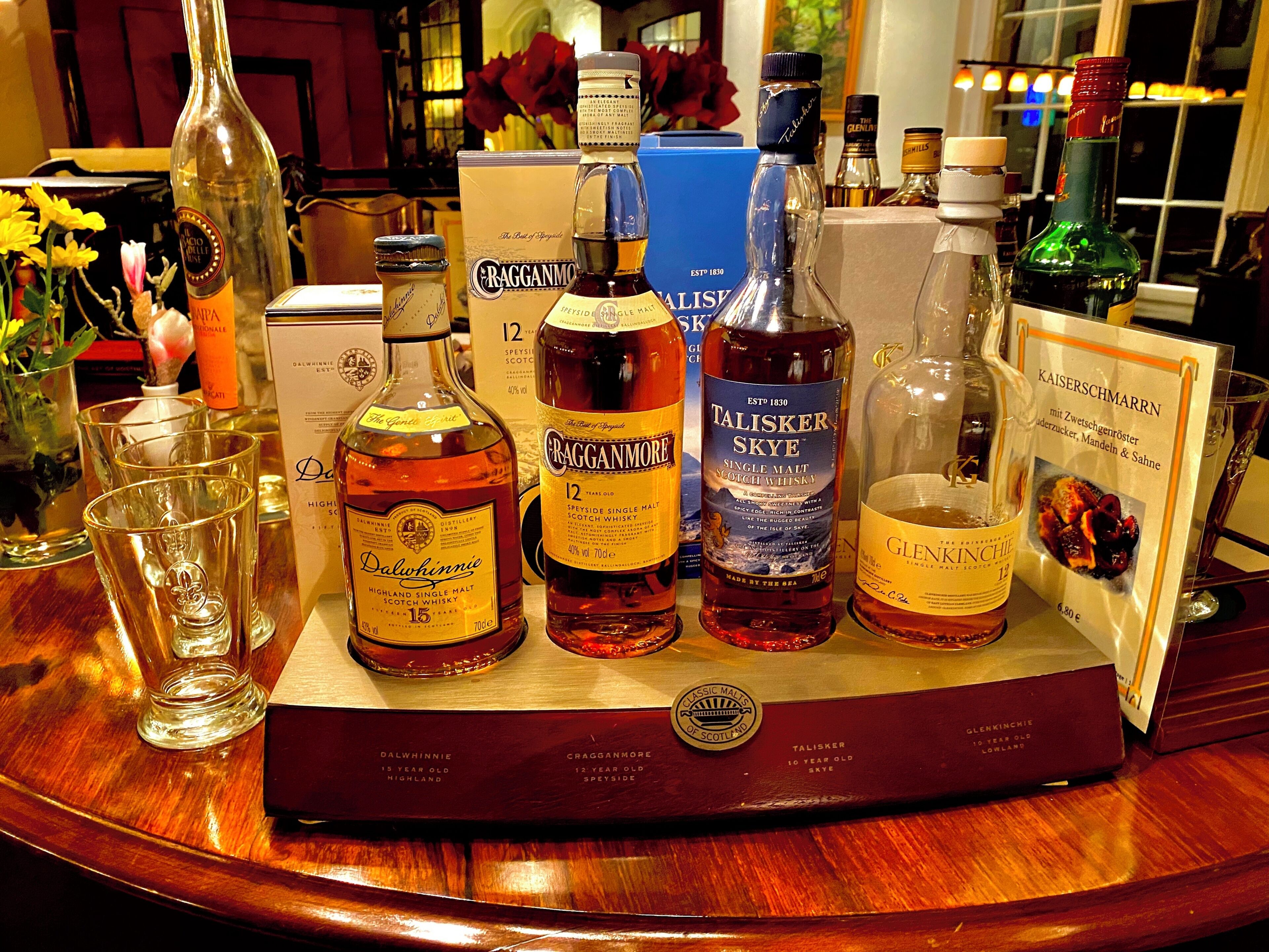 A selection of whisky bottles on a wooden tray with a label indicating 'Classic Malts of Scotland.'