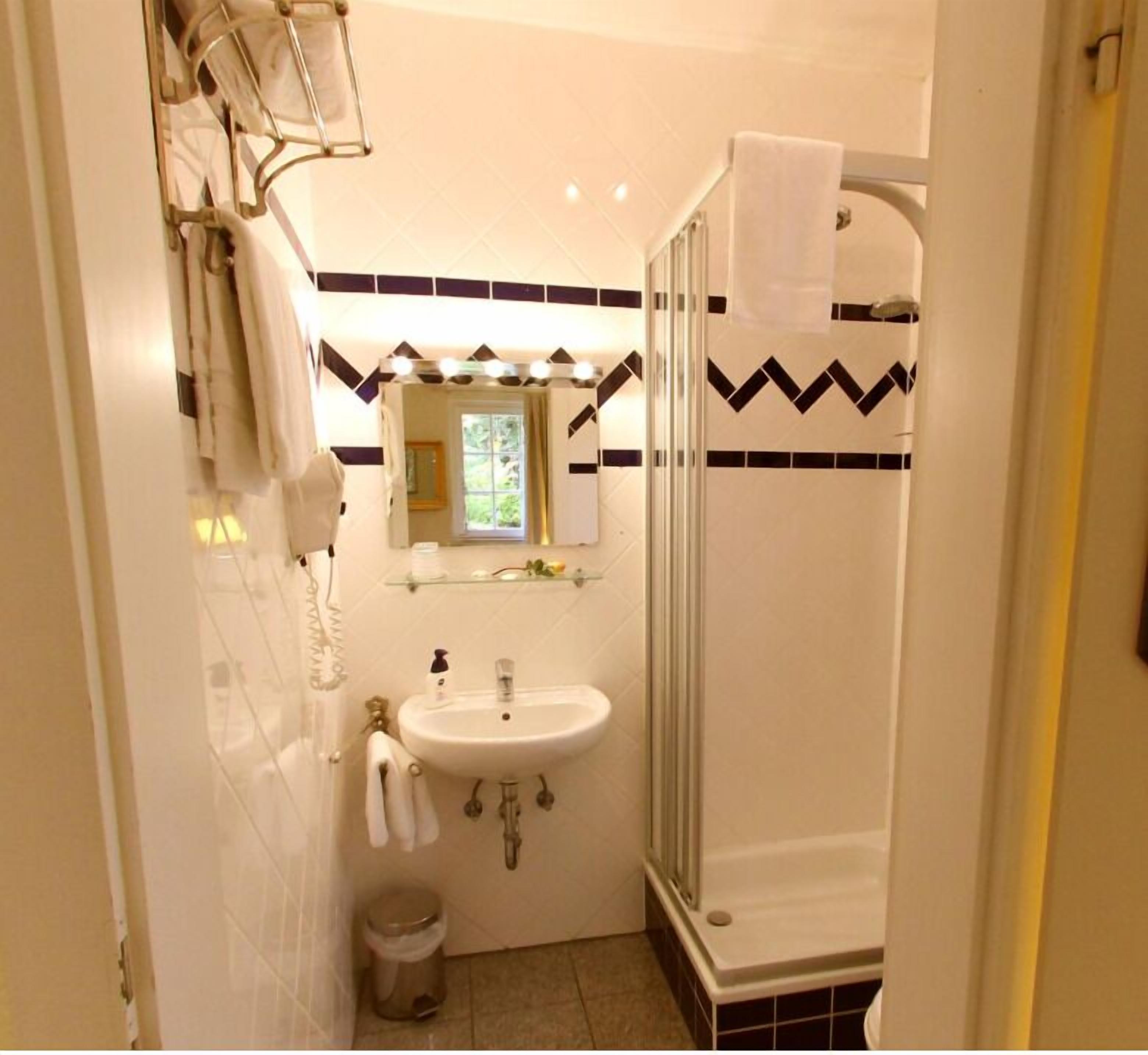 Ein Badezimmer mit Waschbecken, Spiegel, Handtuchhalter und Dusche.