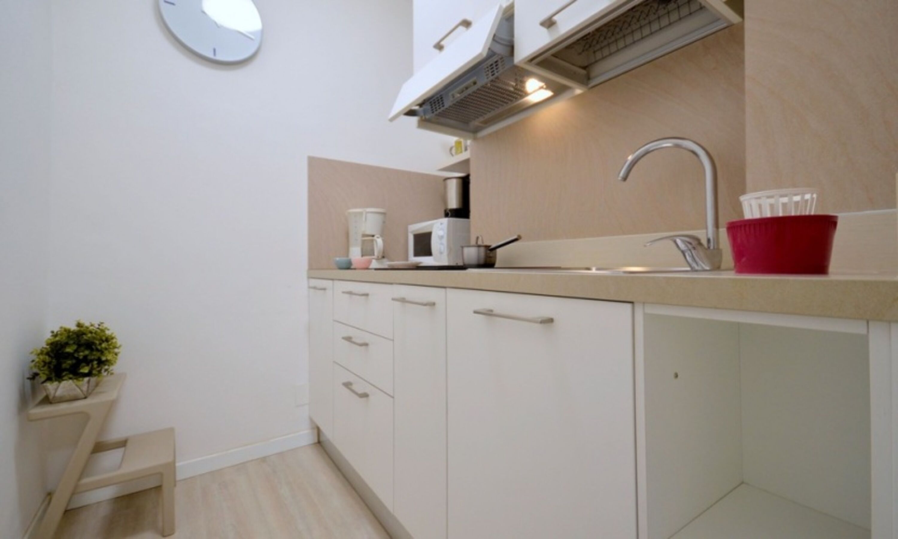 A compact kitchen with a microwave, sink, and cabinets.
