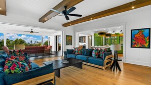 A spacious living room with a large blue sofa set, a wooden coffee table, and a ceiling fan.